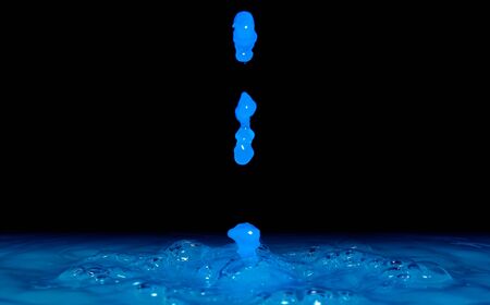Photo of beautiful water drops falling on water and splash on black background