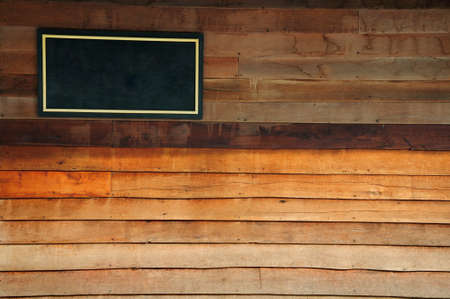 The black wooden sign with golden frame on plywood wall background texture の写真素材