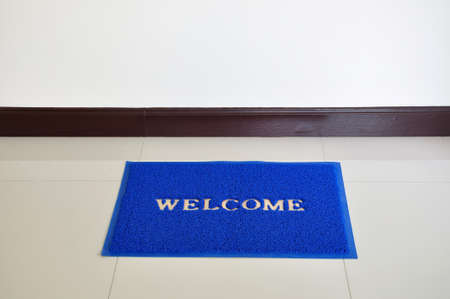 Blue welcome anti-slip door mat on the floor の写真素材