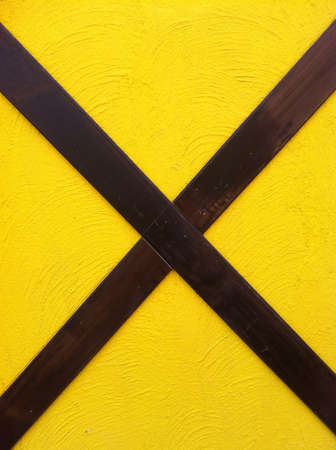 yellow exposed concrete wall with cross wood.の素材