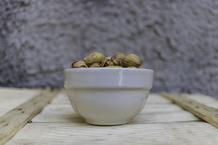 Close up of a bowl full of pistachios on a wooden backgroundの写真素材
