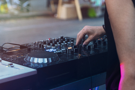 Dj mixing outdoor with in the afternoon - Disc jockey playing vinyl music style for people on street party at night - Fun concept - Purple and yellow filters editing - Focus on consolleの写真素材