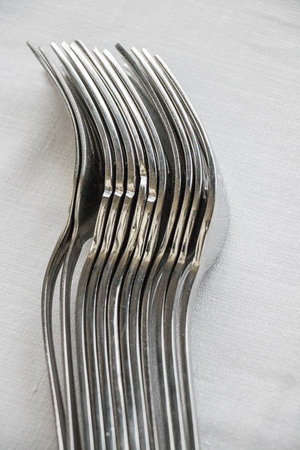 A row of forks in silverware at a restaurant on a white tableclothの写真素材