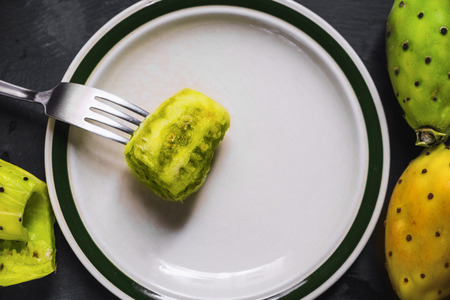 prickly pear figs on a white plate skewered by a forkの写真素材