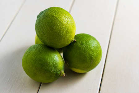 Group of four lime fruits ona a white wooden tableの写真素材