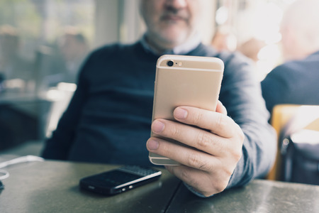 Businessman using his smartphone, one in his hand with the headset and another resting on the tableの写真素材