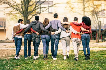 Group of young multiracial people walking arm around shoulders outdoors in a park. Students living enjoying diversity lifestyle concept.の写真素材