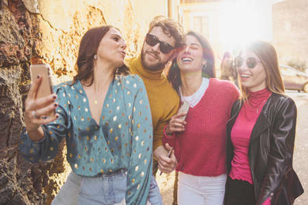 group of young people having fun taking selfie and joking in the streets. Togetherness and...