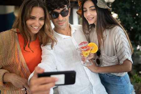 Group of smiling young people watching mobile smartphone and having fun together. Friends using tech concept.の写真素材