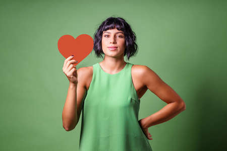 portrait of a happy caucasian woman holding red heart symbolの写真素材
