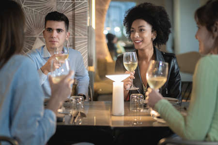 Friends group drinking white wine at coffee bar - People talking and having fun together at fusion food cafe - Friendship concept with happy men and women at fashion restaurantの写真素材