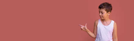 boy pointing isolated on red-orange background wall. Website or social media ad horizontal banner.の写真素材