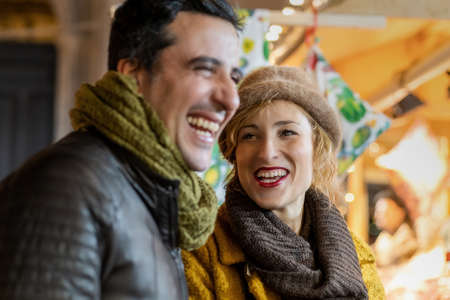 Portrait of mature woman and a man laughing outdoors at the Christmas market.の写真素材