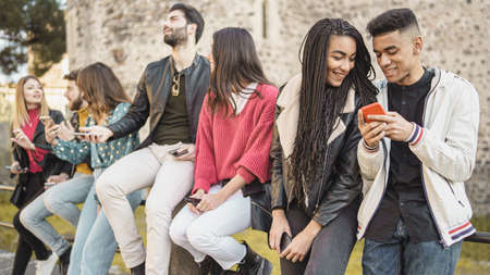 young friends watching viral social media video on mobile cell phone outdoors - Young adult friends using smartphones together -outdoors youth culture conceptの写真素材
