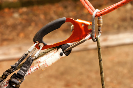 Steel climbing carabiner on a red and yellow safety rope