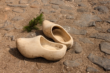 Old peasant shoes carved from wood, built on a rocky roadの写真素材