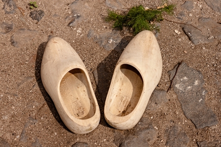 Old peasant shoes carved from wood, built on a rocky roadの写真素材
