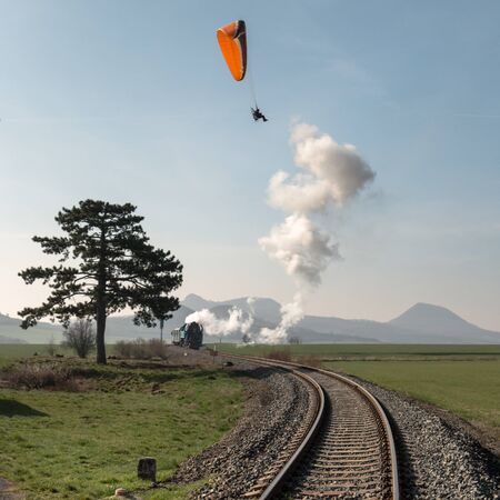 A passenger train, pulled by a steam locomotive, passes through the countryside through the rails....