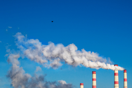 White smoke from the chimneys of the plant against the blue skyの写真素材