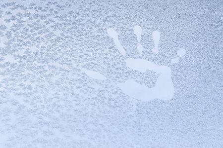 Handprint on a frozen window with snowflakes at -5 Celsius degrees. Winter at the Krasnodar, south Russia.の写真素材