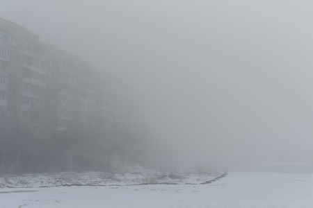 Multi-storey building in the fog. Foggy morning in the winter.の写真素材