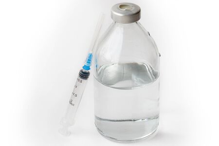 A needle near to a bottle and saline on a white backgroundの写真素材