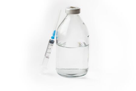 A needle near to a bottle and saline on a white backgroundの写真素材