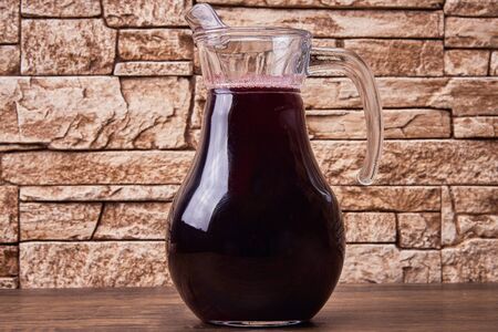 Cherry fruit drink in a glass transparent jug on a tableの写真素材