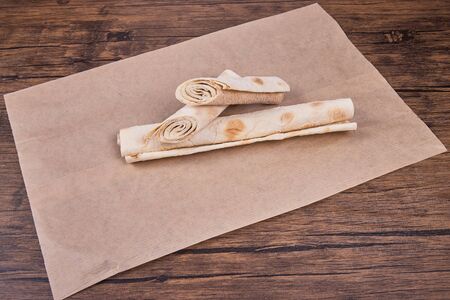 Thin pita bread rolled up on baking paper. Lavash.
