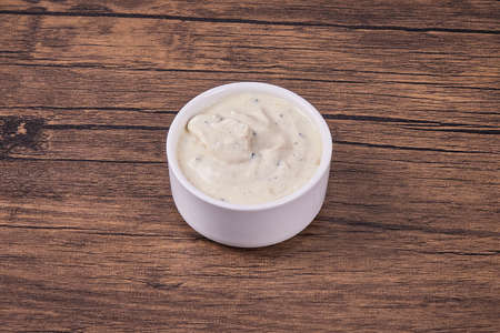 White garlic sauce in a ceramic round gravy boat on a wooden table.の写真素材
