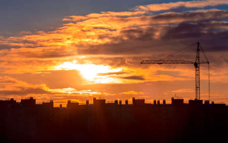 Construction crane near the new homes at sunset
