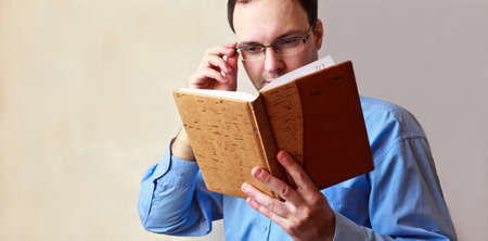 The young man looks at an open diary on a gray background