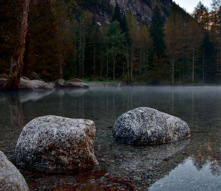 Autumn in Val di Mello with foggy lake and granite stones.の写真素材