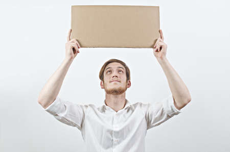 Young Adult Man in White Shirt Holding a Big Cardboard Inscription Above His Head, Looking Up at Itの写真素材