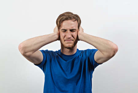 Sad Young Adult Male in Blue T-Shirt Covers His Earsの写真素材