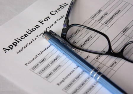 Credit application form with blue pen and glasses on a white background.の写真素材