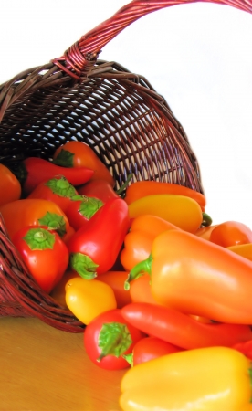 Bright colorful peppers spilling out of a brown wicker basket.の写真素材