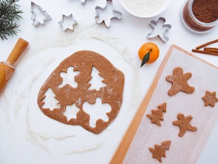 Homemade bakery making, gingerbread cookies in form of Christmas tree, gingerbread man. New year treat for Santa Claus cooking. Homemade bakery, xmas sweet, winter holidays concept. Christmas baking background: dough, cookie cutters tangerines, spice, cocoa, ingredientsの写真素材
