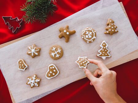 Woman hands holding gingerbread star. Beautiful Christmas background with gingerbread men, Christmas trees and snowflakes, star, with pine, background concept.の写真素材