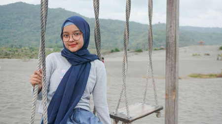 Asian hijab girl is playing swing in the desert, Gumuk Pasir, Yogyakartaの写真素材
