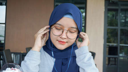 Asian hijab woman listens to music using a headsetの写真素材
