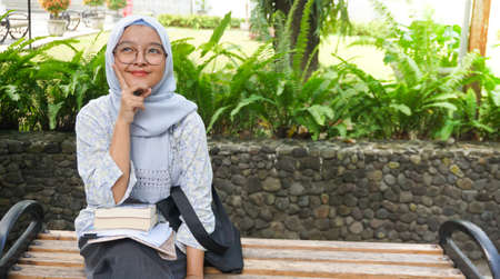 Asian hijab girl reading in the campus garden
