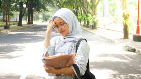 Asian hijab girl reading in the campus gardenの写真素材
