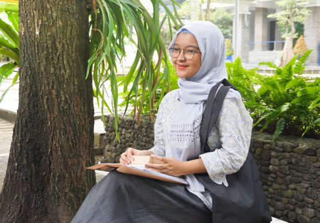 Asian hijab girl reading in the campus gardenの写真素材
