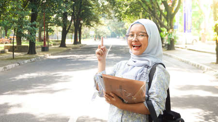Asian hijab girl reading in the campus garden