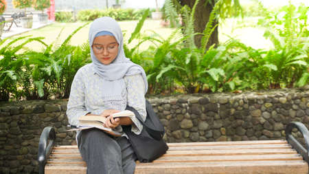 Asian hijab girl reading in the campus gardenの写真素材