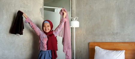 Asian girl is opening a suitcase in the roomの写真素材