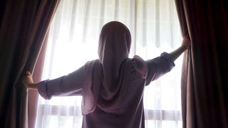 Asian girl is opening a window in the morning