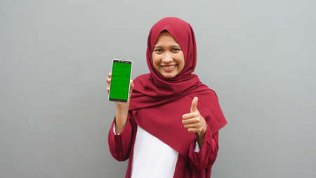 Asian woman pointing to the cellphone with the green screenの写真素材