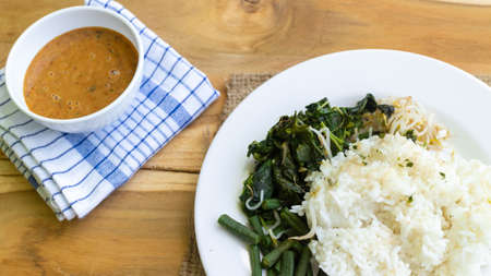 Nasi Pecel. Traditional Javanese rice dish of steamed rice with vegetable salad, peanut dressing,...